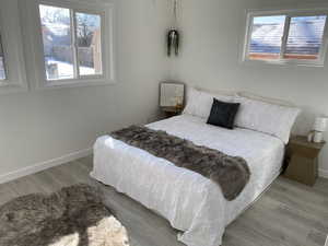 Bedroom with multiple windows, wood finished floors, and baseboards