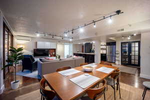 Dining area featuring a textured ceiling, concrete floors, a wall mounted air conditioner, and visible vents