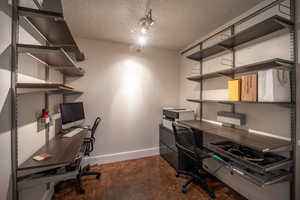 Office area featuring baseboards, concrete flooring, and a textured ceiling