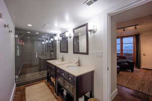 Bathroom featuring double vanity, a stall shower, visible vents, and a sink