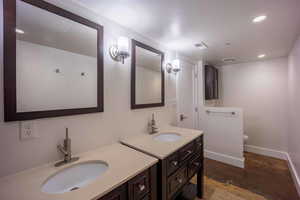 Bathroom with two vanities, a sink, toilet, and baseboards