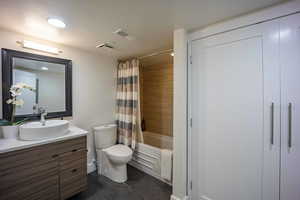 Full bath with visible vents, toilet, tile patterned flooring, shower / bath combo with shower curtain, and vanity