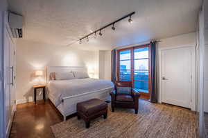 Bedroom featuring a textured ceiling, a wall unit AC, baseboards, and concrete flooring