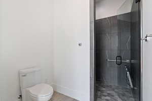 Bathroom with a stall shower, toilet, and baseboards