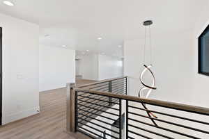 Hall with light wood-style floors, recessed lighting, baseboards, and an upstairs landing