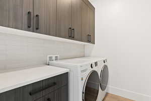 Laundry area with baseboards, light wood-style flooring, cabinet space, and washer and dryer