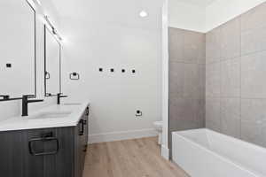 Full bath featuring double vanity, baseboards, a sink, and wood finished floors