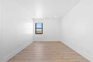 Spare room with light wood-style floors, baseboards, and recessed lighting