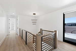 Corridor featuring visible vents, light wood finished floors, an upstairs landing, and baseboards