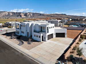 Contemporary home featuring stucco siding, a mountain view, a balcony, a residential view, and driveway