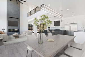 Dining area featuring light wood-style floors, a fireplace, a high ceiling, and recessed lighting