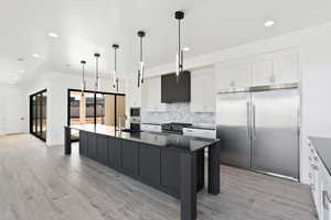 Kitchen featuring dark countertops, pendant lighting, a sink, and built in appliances