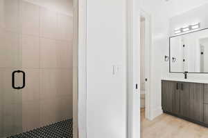 Bathroom featuring toilet, a stall shower, wood finished floors, and vanity