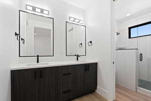 Bathroom with a sink, a shower stall, and wood finished floors