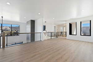 Unfurnished room featuring baseboards, light wood-type flooring, a mountain view, and recessed lighting