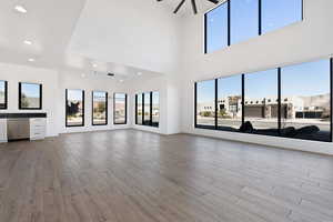 Unfurnished living room with ceiling fan, a residential view, light wood-style flooring, and recessed lighting