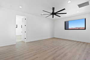 Empty room featuring light wood-style flooring, visible vents, baseboards, and recessed lighting