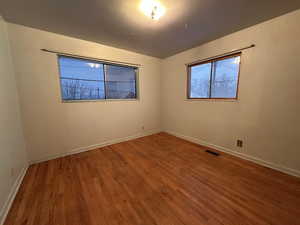 Unfurnished room with wood finished floors, visible vents, and baseboards