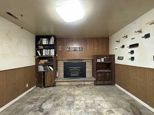 Living area featuring a wainscoted wall, a wood stove, visible vents, and wooden walls