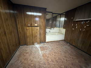 Bathroom featuring wooden walls and a bath