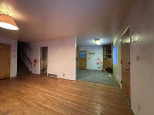 Spare room featuring visible vents, stairway, and wood finished floors