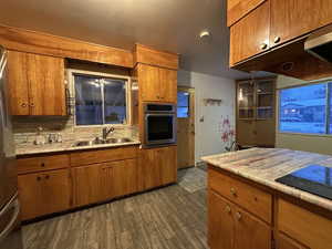 Kitchen featuring brown cabinets, appliances with stainless steel finishes, light countertops, and a sink