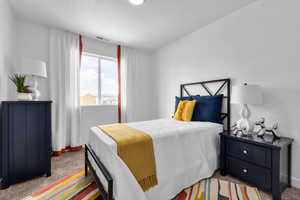 Bedroom with baseboards, visible vents, and light colored carpet