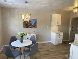 Dining area with a chandelier, dark wood finished floors, a textured ceiling, and baseboards