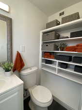 Bathroom with toilet, visible vents, and vanity