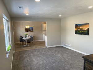 Dining area with baseboards, visible vents, dark colored carpet, and a textured ceiling