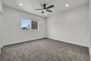 Carpeted spare room featuring baseboards, ceiling fan, and recessed lighting