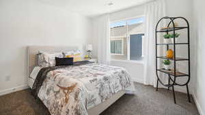 Bedroom with baseboards, visible vents, and dark carpet