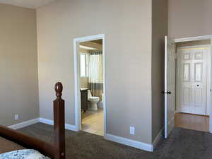 Bedroom featuring baseboards, ensuite bathroom, and light colored carpet