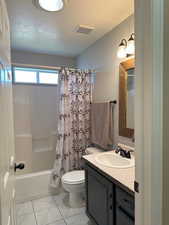 Full bathroom featuring a textured ceiling, vanity, visible vents, tile patterned floors, and shower / bath combination with curtain