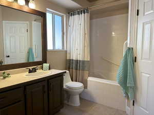 Bathroom featuring shower / tub combo with curtain, vanity, toilet, and tile patterned floors