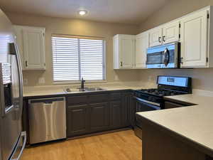 Kitchen with a sink, stainless steel appliances, light countertops, and white cabinets