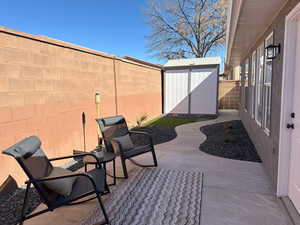 View of patio / terrace featuring a shed, a fenced backyard, and an outbuilding