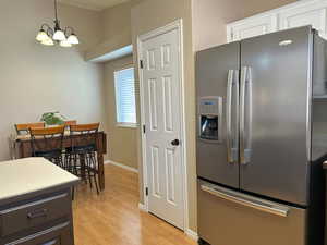 Kitchen featuring stainless steel fridge with ice dispenser, light wood-style flooring, decorative light fixtures, light countertops, and white cabinetry