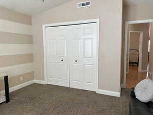 Unfurnished bedroom with baseboards, visible vents, a textured ceiling, carpet floors, and a closet