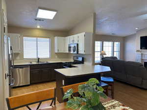 Kitchen with stainless steel appliances, a peninsula, a sink, white cabinets, and open floor plan