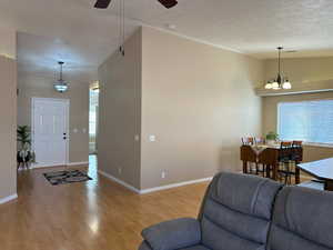 Living room featuring light wood finished floors, baseboards, vaulted ceiling, and ceiling fan with notable chandelier