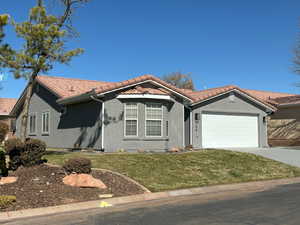 View of front of home featuring a garage, a tiled roof, concrete driveway, stucco siding, and a front lawn