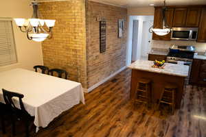 Kitchen with a kitchen bar, light stone counters, a center island, dark hardwood / wood-style floors, and stainless steel appliances