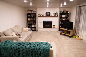 Living room with a textured ceiling, light carpet, and a brick fireplace