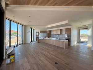 Kitchen featuring modern cabinets, open floor plan, double oven, freestanding refrigerator, and decorative backsplash
