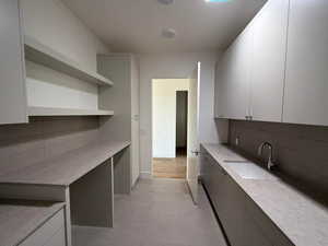 Kitchen featuring decorative backsplash, light countertops, open shelves, and white cabinets