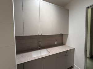 Kitchen featuring backsplash, light countertops, and gray cabinetry