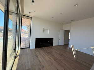 Unfurnished living room with wood finished floors, a wall of windows, and recessed lighting