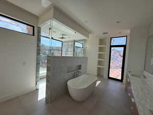 Bathroom featuring a walk in shower, a freestanding tub, vanity, and plenty of natural light