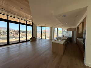 Kitchen featuring floor to ceiling windows, wood finished floors, open floor plan, freestanding refrigerator, and light countertops